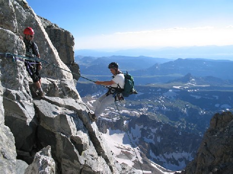 Jeff rapelling down a cliff face while Andrew looks on.